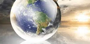 Crystal ball reflecting globe of the earth on sunset with clouds background